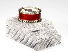 a glass bottle with a red lid and silver trim on it's cap is shown in front of a white background