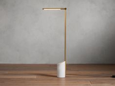 a lamp that is on top of a wooden floor in front of a gray wall