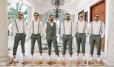 a group of men standing next to each other in front of a chandelier