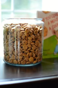 a glass jar filled with dog food next to a book