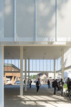 people are walking around in an open area with white walls and large windows on each side