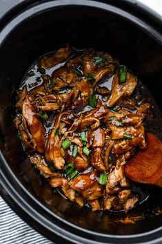 the slow cooker is full of chicken and vegetables with a wooden spoon in it