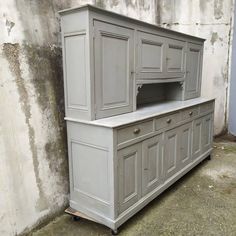 a gray cabinet sitting next to a wall with an open shelf on the top and bottom