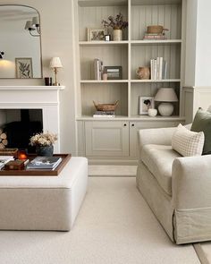 a living room filled with furniture and a fire place under a mirror on the wall