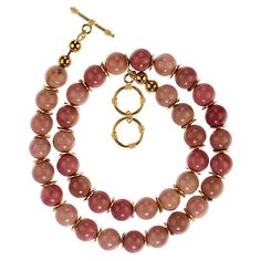 Introducing the 19-Inch Natural Rhodonite Necklace – a stunning piece designed to captivate with its soft, rosy hues. This beautiful necklace features 10mm opaque rhodonite beads in shades of pink and rose, showcasing the natural elegance of the stone. Each bead is accented with charming gold-tone flutter details, adding a touch of warmth and sophistication to the design. Perfectly sized at 19 inches, this necklace sits gracefully on the neckline, making it an ideal accessory for both casual and Rhodonite Necklace, Pink Topaz Necklace, Amethyst Rock, Ruby Beads, Topaz Necklace, Pink Topaz, Modern Necklaces, Shades Of Pink, Cool Necklaces