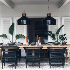 a dining room table with black chairs and potted plants