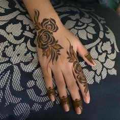 a woman's hand with hennap and flowers painted on the top of it