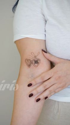 a woman's stomach with two hearts and a bow tattoo on her left side