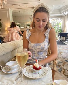 a woman sitting at a table with a glass of wine and cake in front of her