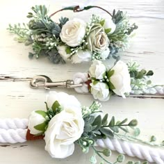 two white flowers and greenery are tied to ropes