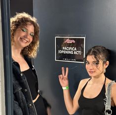 two women standing next to each other in front of a sign that says pacifica opening act