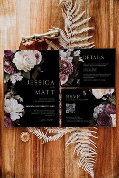 the wedding stationery is laid out on a wooden table with flowers and fern leaves