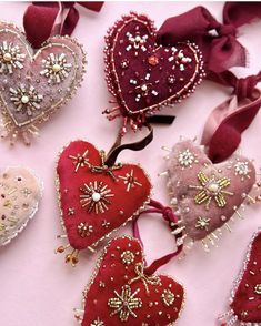 several heart shaped brooches are arranged on a pink surface with ribbons and bows