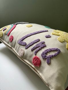 a decorative pillow with crocheted letters on it