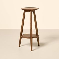 a wooden stool with a round seat on the bottom, and a small shelf below it