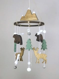 a wooden mobile with animals and trees hanging from it's sides on a gray wall