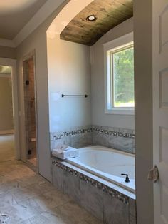 an empty bathroom with a large tub in the corner and tile flooring on the walls