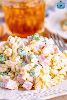 a white plate topped with macaroni salad next to a cup of tea