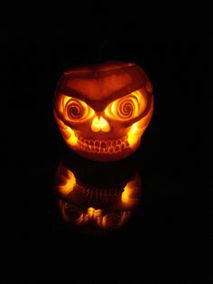 a pumpkin carved to look like an evil face with glowing eyes and mouth, lit up in the dark