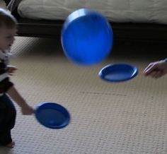 a little boy playing with blue frisbees on the floor