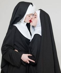 two women dressed in nun costumes kissing each other