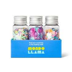 three jars filled with confetti and sprinkles on top of a blue box