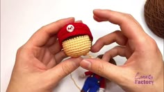 someone is knitting a knitted toy in the shape of an acorn with a red hat