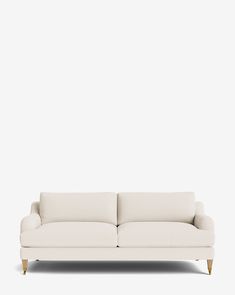 a white couch sitting on top of a wooden floor next to a wall with a light colored