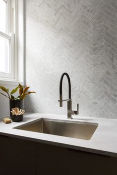 a kitchen sink sitting under a window next to a potted plant