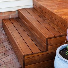 a wooden bench sitting next to a flower pot on top of a brick floored patio