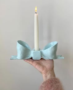 a person holding a candle in their hand with a light blue bow on the top