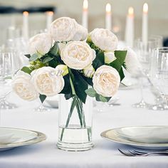 a vase filled with white flowers sitting on top of a table next to silverware