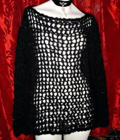 a white mannequin wearing a black knitted sweater with holes on the shoulders