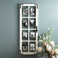 a vase filled with flowers sitting next to a wall mounted photo frame on a green wall