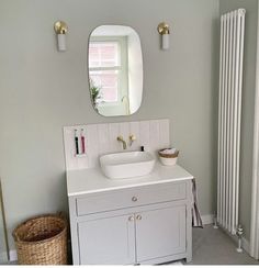 a white sink sitting under a bathroom mirror next to a radiator in a room