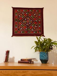 a potted plant sitting on top of a wooden table next to a wall hanging