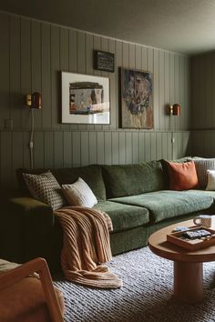 a living room with green couches and pictures on the wall above them, along with coffee table