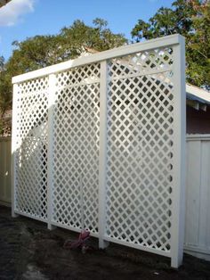 a white fence that is next to a house with trees in the backgroud