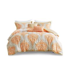 an orange and white comforter set with pillows