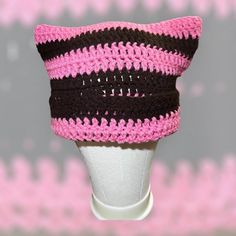 a pink and black crocheted hat on top of a white mannequin head