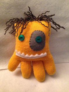 a yellow stuffed animal with dreadlocks on it's head and green eyes