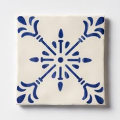 a blue and white tile with an intricate design on the front, against a white background