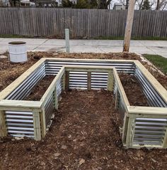 a wooden garden bench sitting in the middle of a dirt field next to a fence