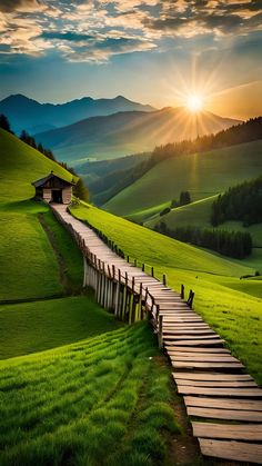 the sun is setting over a grassy hill with wooden steps leading to a small cabin