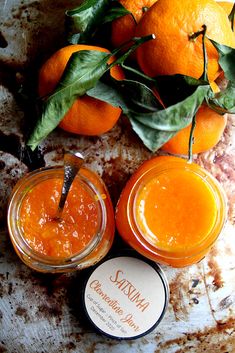 two oranges sitting next to each other on top of a table with some sauce in jars