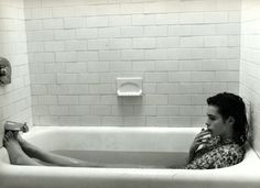 a woman sitting in a bathtub with her feet up on the edge of the tub