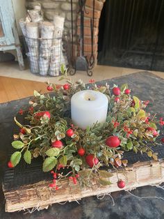 a candle is sitting on top of a book with berries and greenery around it