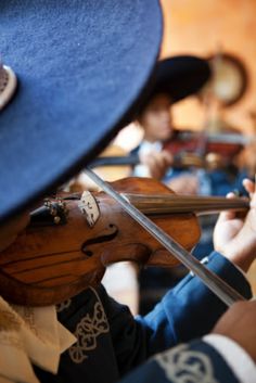 a close up of a violin being played by someone wearing a blue hat and holding it in their hands