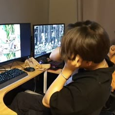 a young boy sitting in front of two computer monitors