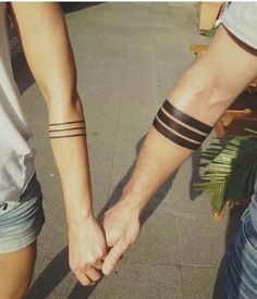 two people holding hands with tattoos on their arms